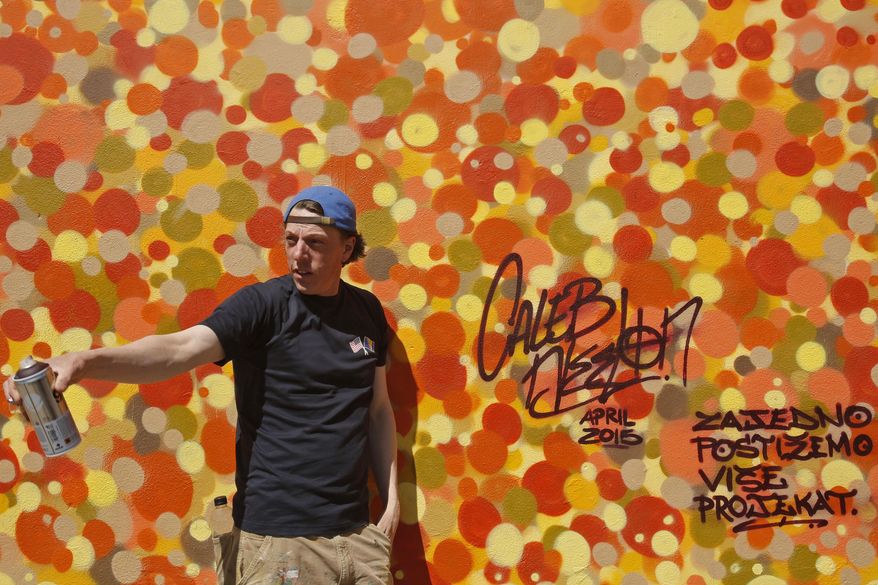 American graffiti artists Caleb Neelon poses for photo in front over work on a wall in Bosnian capital of Sarajevo, on Tuesday, April, 21.2015. American graffiti artists Caleb Neelon, the author of street murals in numerous cities around the world, has gathered youths from different sides of Bosnia’s ethnic divide to jointly work on a peace-promoting project. (AP Photo/Amel Emric)