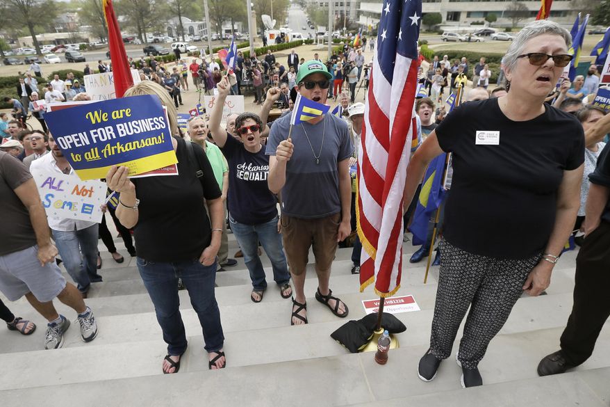 In this photo taken April 1, 2015, pro gay rights demonstrators gather at the Arkansas state Capitol in Little Rock, Ark. After the state became the epicenter of a fight over measures critics say are anti-gay, several Arkansas cities are trying to stem any potential fallout with efforts to push back on the new laws and expand anti-discrimination protections. (AP Photo/Danny Johnston)