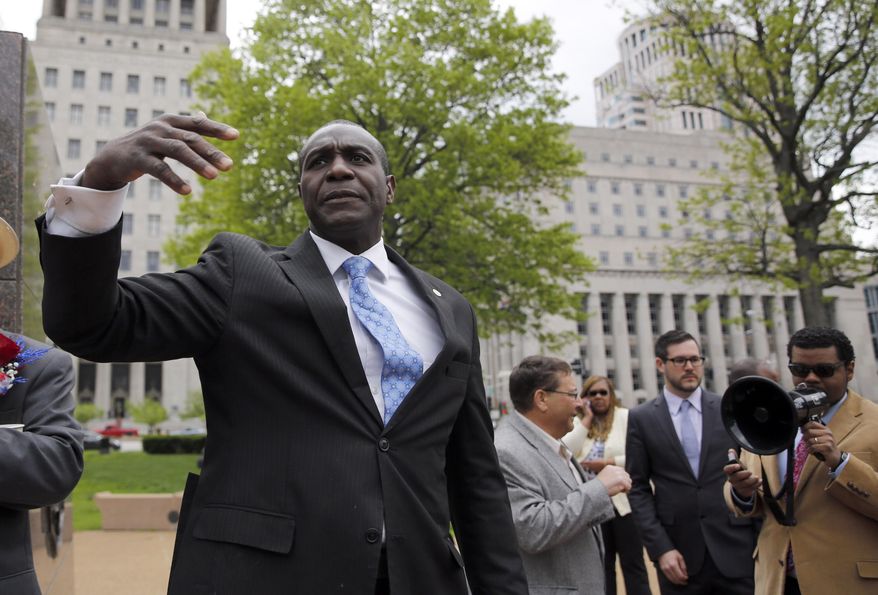 St. Louis Board of Aldermen President Lewis Reed calls out to other members of the board to gather and be given the oath of office in a park across the street from City Hall Tuesday, April 21, 2015, in St. Louis. The swearing in was moved outside after City Hall was evacuated Tuesday when two suspicious cylinders and a bag were found at three entrances to the sprawling government building downtown. (AP Photo/Jeff Roberson)