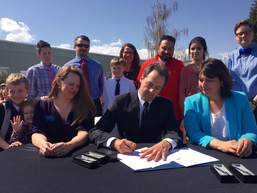 Montana Gov. Steve Bullock signs the Bully Free Montana Act Tuesday, April 21, 2015, at Jefferson Elementary in Helena, Mont., while bill sponsor Rep. Kim Dudik, left, and Superintendent of Public Instruction Denise Juneau look on. (AP Photo/Lisa Baumann)