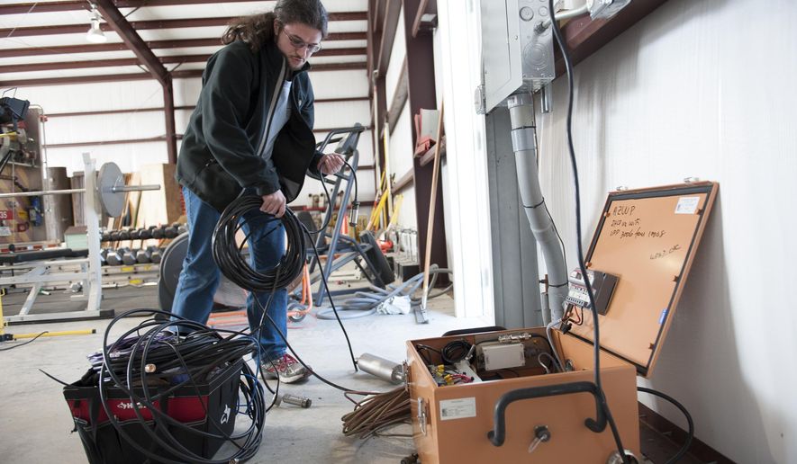 This handout photo, taken Jan. 16, 2014, provided by Southern Methodist University, shows Remi Oldham, an SMU geophysics graduate student, running a cable to connect the seismometer to communications interface equipment housed in the orange metal box in Willow Park, Texas. The interface equipment allows the transmission of the data collected by the seismometer back to SMU. With real-time monitors, scientists linked a swarm of small earthquakes west of Fort Worth, Texas, to nearby natural gas wells and wastewater injection. In 84 days from November 2013 to January 2014, the area around Azle, Texas, shook with 27 magnitude 2 or greater earthquakes, while scientists at Southern Methodist University and the U.S. Geological Survey monitored the shaking. It’s an area that had no recorded quakes for 150 years on faults that “have been inactive for hundreds of millions of years,” said SMU geophysicist Matthew Hornbach. (Hillsman Stuart Jackson/SMU via AP)