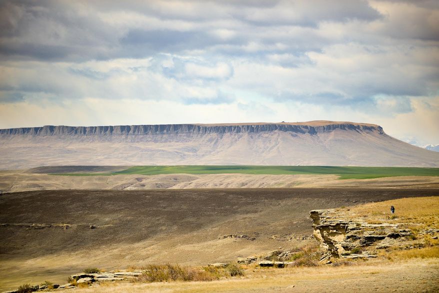 In this photo taken on April 12, 2015, visitors explore the rim of the buffalo jump at First Peoples Buffalo Jump State Park with Square Butte visible in the distance near Ulm, Mont. First Peoples Buffalo Jump State Park, just west of the Missouri River near Ulm, celebrates the culture and history of the Great Plains and the park is now on track to become a National Historic Landmark. (Ben Pierce/Bozeman Daily Chronicle via AP)