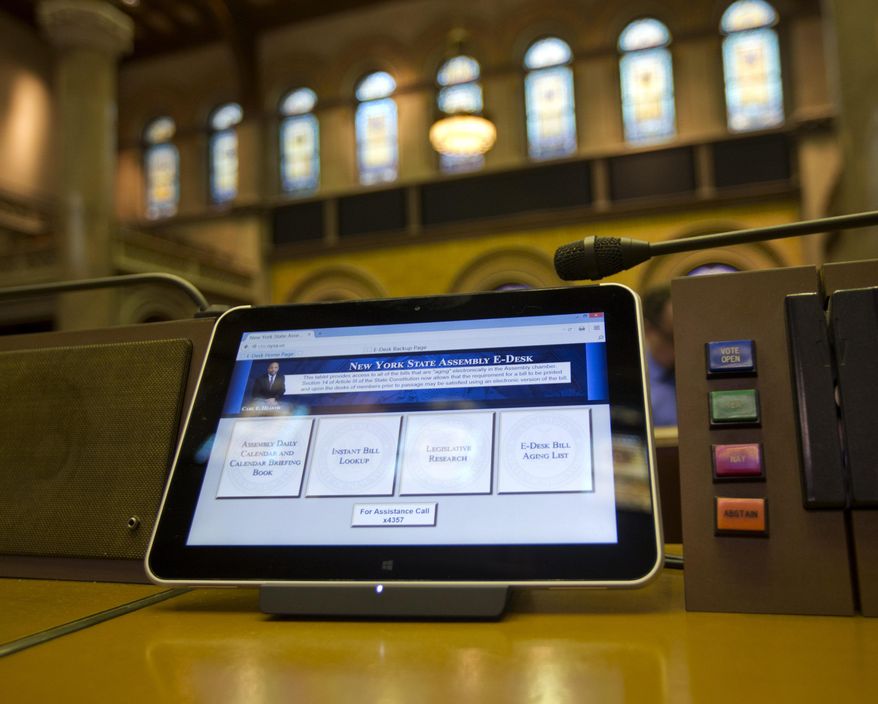 An electronic tablet sits on a legislator's desk in the Assembly Chamber at the Capitol on Wednesday, April 22, 2015, in Albany, N.Y. The 150 desks in the ornate chamber of the Assembly now have computer tablets mounted, with four large boxes on the screens that legislators can click to see their calendars, look up bills, research legislation and find out where a particular measure stands in the aging process before it can be voted on. (AP Photo/Mike Groll)