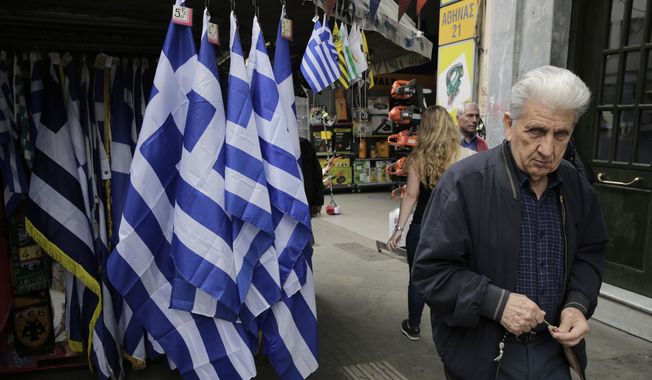 An man walk past a kiosk with Greek flags for sale in central Athens, Thursday, April 23, 2015. Greece is running perilously short of cash amid an impasse in bailout talks with its international creditors. Eurozone finance ministers are to meet in Riga, Latvia, on Friday but hopes of a deal on Greece there have diminished. (AP Photo/Petros Giannakouris)