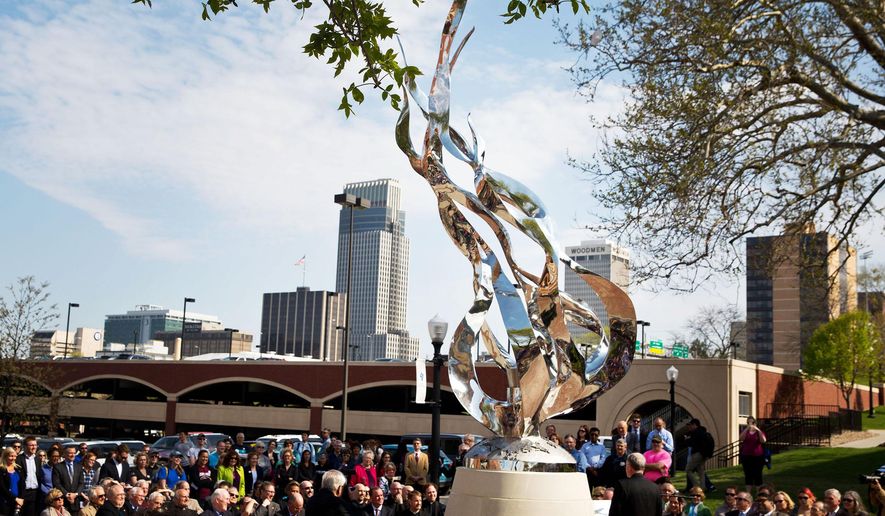 This April 23, 2015 photo shows "The Flame" a sculpture by Littleton Alston during a dedication ceremony in Omaha, Neb. The 20-foot-tall, stainless steel sculpture at Omaha's Creighton University features a flame that will remain lit day and night. (Chris Machian/The World-Herald via AP) MAGS OUT; ALL NEBRASKA LOCAL BROADCAST TELEVISION OUT