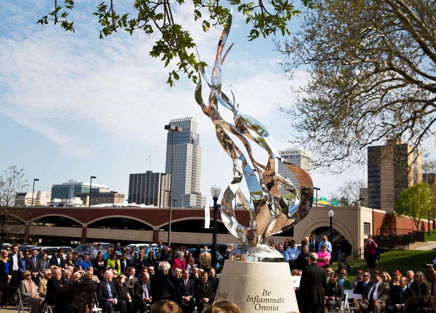 This April 23, 2015 photo shows "The Flame" a sculpture by Littleton Alston during a dedication ceremony in Omaha, Neb. The 20-foot-tall, stainless steel sculpture at Omaha's Creighton University features a flame that will remain lit day and night. (Chris Machian/The World-Herald via AP) MAGS OUT; ALL NEBRASKA LOCAL BROADCAST TELEVISION OUT