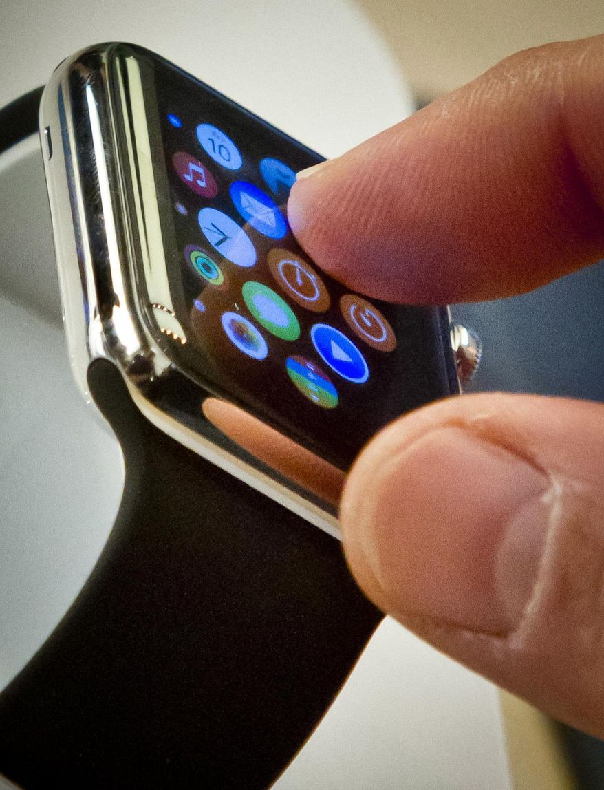 FILE - In this April 10, 2015 file photo, a customer examines Apple's new watch in New York. The first batch of Apple Watches will arrive in people’s homes and offices Friday April 24, 2015. (AP Photo/Bebeto Matthews)