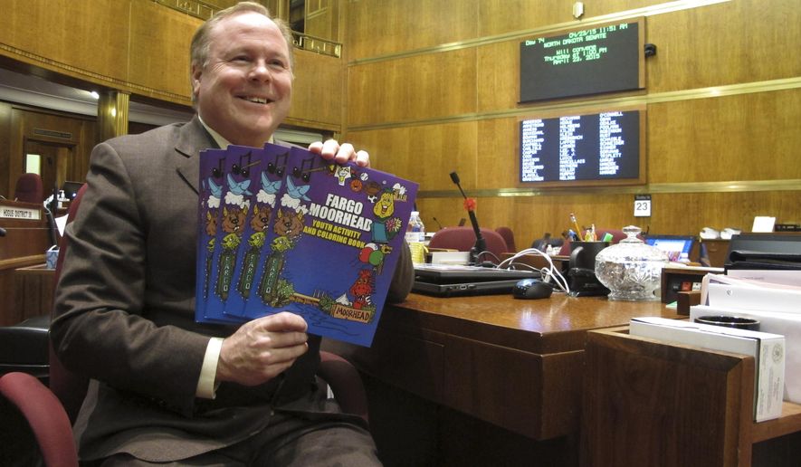 In this Thursday, April 23, 2015 photo, North Dakota state Sen. Tim Flakoll, of Fargo, poses in the Senate chambers in Bismarck with copies of a coloring book he designed along with artist Steve Stark, of Fargo. The book highlights various landmarks and institutions in the Fargo and Moorhead, Minnesota, area. (AP Photo/Dave Kolpack)