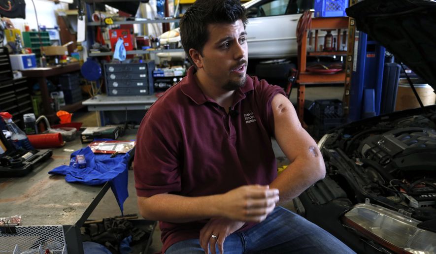 In this April 21, 2015 photo, Aurora movie theater shooting survivor Pierce O’Farrill shows some of his now-healed bullet wounds while giving an interview inside the repair shop at the Denver Rescue Mission&#39;s vehicle donation program, which he runs, in Denver. Nearly three years may have passed since James Holmes, wearing body armor, opened fire in a deadly attack at a packed Colorado movie theater, but many survivors - and relatives of the dead - are still trying to make sense of the shooting. (AP Photo/Brennan Linsley)