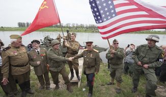 Amateur actors re-enact the link-up of Soviet and American troops during the 70th anniversary of the Elbe Day in Torgau, eastern Germany, Saturday, April 25, 2015. The WW II link-up of US and Soviet Forces occurred here at the river Elbe on April 25, 1945. (AP Photo/Jens Meyer)