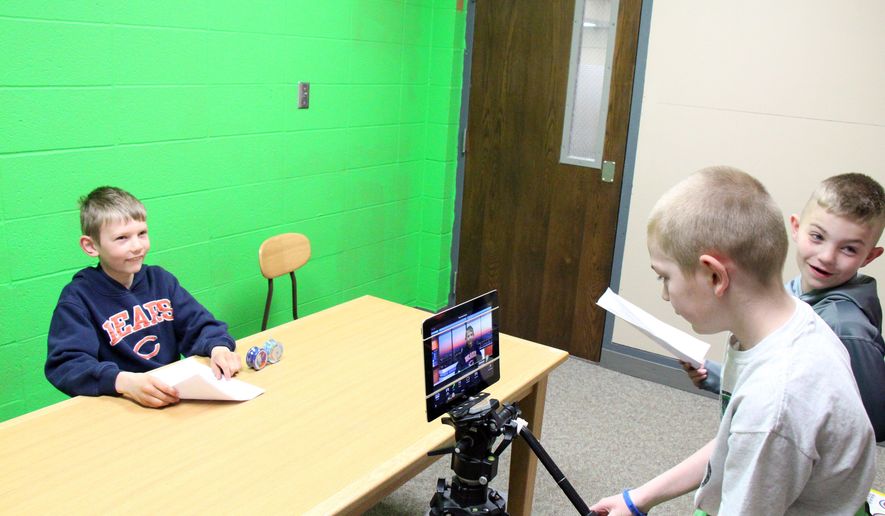 BCLUW fourth grader Connor Lynch, left, practices delivering the Comet News weekly announcements as Alex Paxaon films and “Character Counts” reporter Chance Cordes stands at right on April 15, 2015 in Conrad, Iowa. Using an iPad to record video, they deliver the week's news. (Bennet Goldstein/The Times-Republican via AP)