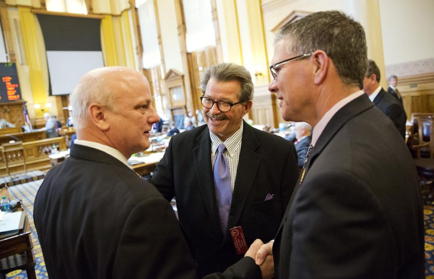 FILE- In this March 26, 2015 file photo, State Rep. Alan Powell, R-Hartwell, center, celebrates the passing of his ride sharing bill with Sen. Brandon Beach, R-Alpharetta, left, and Rep. Dale Rutledge, R-McDonough, right, after it was passed on the Senate floor in Atlanta. Popular ride-hailing services such as Uber and Lyft are fighting lawsuits in Atlanta and many other cities by cab drivers, taxi and limousine companies claiming the new techno-kids on the block are siphoning off passengers and profits by skirting regulations that make consumers safer. (AP Photo/David Goldman, File)