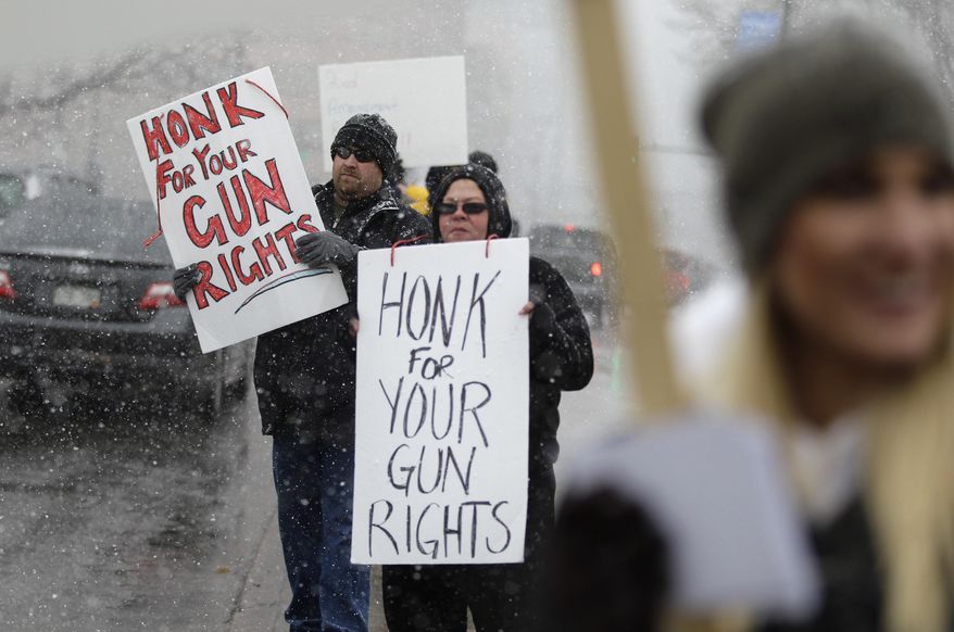 In this March 4, 2013, file photo, opponents of proposed gun control bills being considered by the Colorado Legislature hold signs to those passing in cars, in front of the State Capitol, in Denver. (AP Photo/Brennan Linsley, file)