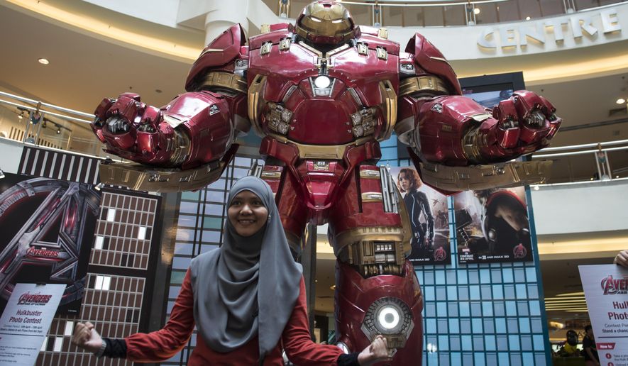 FILE - In this April 10, 2015 file photo, a Malaysian Muslim woman poses with a Hulkbuster statue from "Avengers: Age of Ultron" at a mall in Kuala Lumpur, Malaysia. Several hundred movie theaters in Germany have refused to screen the new "Avengers" film in a dispute over rental fees with Disney. News agency dpa reported that 686 theaters in 193 mostly small towns refused to show "Avengers: Age of Ultron," which opened on Thursday, April 23. (AP Photo/Joshua Paul, File)