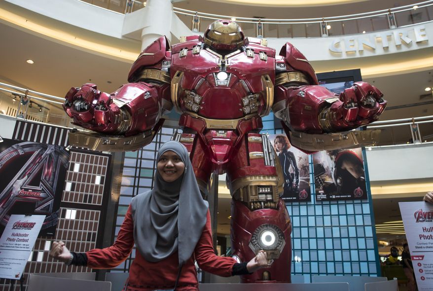 FILE - In this April 10, 2015 file photo, a Malaysian Muslim woman poses with a Hulkbuster statue from "Avengers: Age of Ultron" at a mall in Kuala Lumpur, Malaysia. Several hundred movie theaters in Germany have refused to screen the new "Avengers" film in a dispute over rental fees with Disney. News agency dpa reported that 686 theaters in 193 mostly small towns refused to show "Avengers: Age of Ultron," which opened on Thursday, April 23. (AP Photo/Joshua Paul, File)