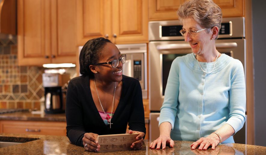 In this March 31, 2015 photo, St. Francis DeSales senior Daijah Scott, left, and her Big Sister Katie Brosmer share a laugh in Brosmer's kitchen in Columbus, Ohio. Brosmer was recently named Big Sister of the Year by Big Brothers Big Sisters. (Adam Cairns/The Columbus Dispatch via AP)