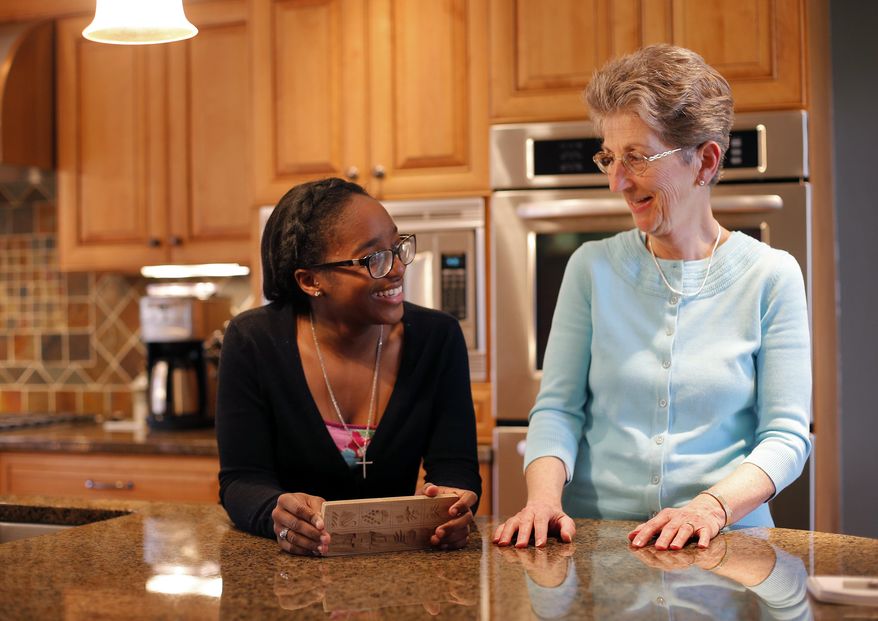 In this March 31, 2015 photo, St. Francis DeSales senior Daijah Scott, left, and her Big Sister Katie Brosmer share a laugh in Brosmer's kitchen in Columbus, Ohio. Brosmer was recently named Big Sister of the Year by Big Brothers Big Sisters. (Adam Cairns/The Columbus Dispatch via AP)