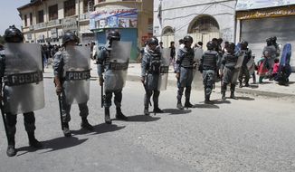 Afghan security forces stand guard during a protest demanding justice for a woman who was beaten to death by a mob after being falsely accused of burning a Quran more than one month ago, in downtown Kabul, Afghanistan, Monday, April 27, 2015. (AP Photo/Allauddin khan)
