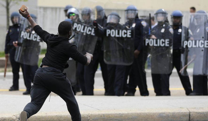 A man throws a brick at police Monday following the funeral of Freddie Gray in Baltimore. (Associated Press)