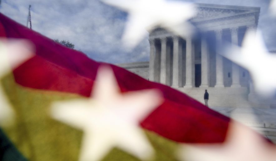 A rainbow colored flag, seen through an American flag, flies in front of the Supreme Court in Washington, Monday, April 27, 2015, as the Supreme Court is set to hear historic arguments in cases that could make same-sex marriage the law of the land. . (AP Photo/Andrew Harnik)