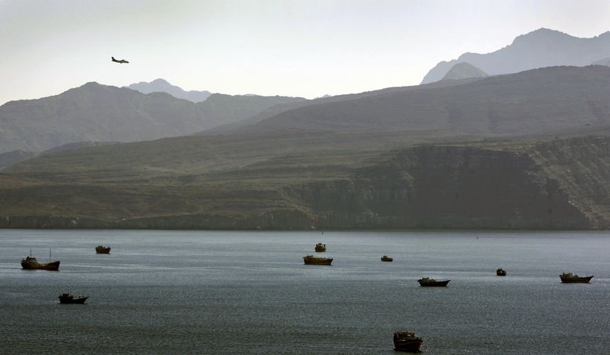 A plane flies over the mountains in south of the Strait of Hormuz as the trading dhows and ships are docked on the Persian Gulf waters near the town of Khasab, in Oman. (AP Photo/Kamran Jebreili, File)