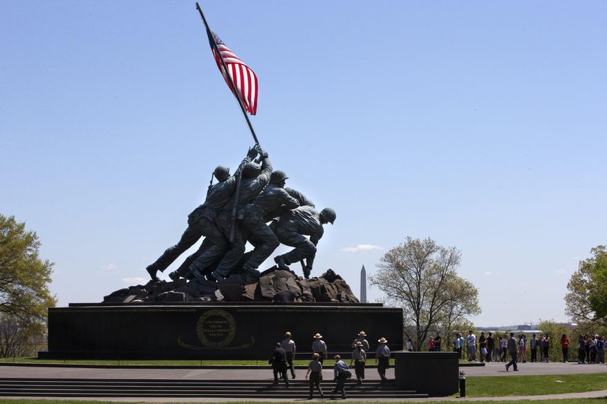 National Park Service rangers walk toward the U.S. Marine Corps War Memorial in Arlington, Va., Wednesday, April 29, 2015. The famous bronze U.S. Marine Corps War Memorial overlooking Washington that depicts Marines raising the American flag at Iwo Jima during World War II has begun turning green with age but now will be restored with a $5.37 million gift. Philanthropist David Rubenstein announced Wednesday that he will give the National Park Foundation the funds needed to wash, wax and restore the memorial and its plaza and landscaping. Improvements are also planned for the memorial's signage and access for handicapped visitors. The project will also restore the memorial's engravings to be much brighter. (AP Photo/Jacquelyn Martin)