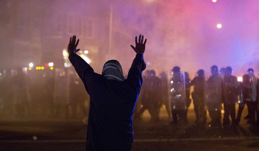 A protestor faces police enforcing a curfew Tuesday night in Baltimore. A line of police behind riot shields hurled smoke grenades and fired pepper balls at dozens of protesters to enforce a citywide curfew. (Associated Press)