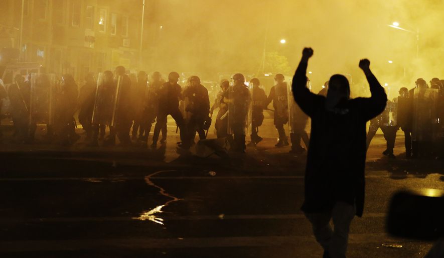 Police in riot gear advance on the crowd after a 10 p.m. curfew went into effect Tuesday in Baltimore. (Associated Press)