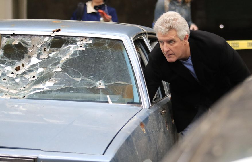 FILE - In this Friday, April 10, 2015, file photo, Cuyahoga County Common Pleas Judge John O'Donnell reaches into the car that was driven by Timothy Russell, in Cleveland. O’Donnell is about to decide the highest-profile case of his judicial career: Whether prosecutors have proved that a Cleveland police officer is guilty of voluntary manslaughter charges in the deaths of two unarmed citizens after a high-speed chase in 2012. (AP Photo/Aaron Josefczyk, Pool, File)
