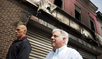 Maryland Gov. Larry Hogan, right, walks past a burned out shoe store while visiting local businesses, Thursday, April 30, 2015, in Baltimore, that were damaged in the rioting following Monday&#39;s funeral for Freddie Gray, who died in police custody. (AP Photo/David Goldman)