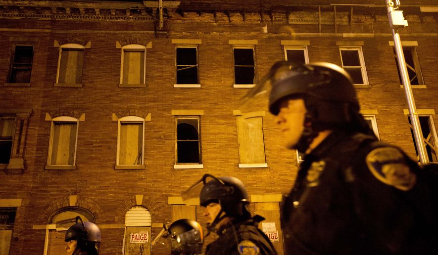 Police in riot gear walk past boarded up row homes after a 10 p.m. curfew went into effect Wednesday, April 29, 2015, in Baltimore. The curfew was imposed after unrest in Baltimore over the death of Freddie Gray while in police custody. (AP Photo/David Goldman)