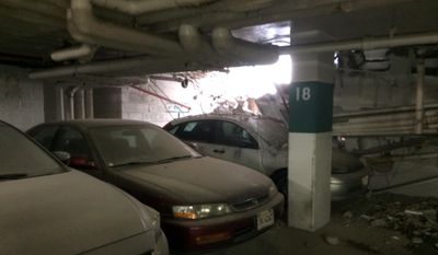 Parked cars are seen near a part of collapsed structure at the Watergate complex in Washington, Friday, May 1, 2015. District of Columbia rescuers were responding to a structural collapse in the garage at the Watergate complex where one person may be trapped. A spokesman said three stories of the garage apparently collapsed. The area was under construction at the time. (Minh Tran via AP)