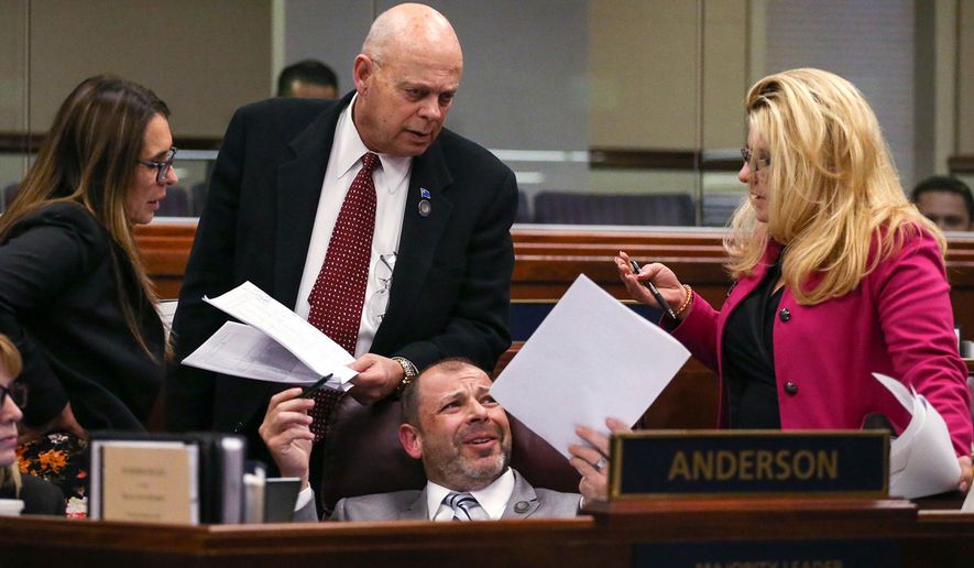 FILE - In this April 21, 2015 file photo , Nevada Assembly Republicans, standing from left, Victoria Seaman, Jim Wheeler and Michele Fiore talk with Assembly Majority Leader Paul Anderson, center, on the Assembly floor at the Legislative Building in Carson City, Nev. While acknowledging the difficulties in working with the 24 other Republicans in his caucus, Anderson says he’s extremely confident that the group will be able to work together and find a way to fund Gov. Brian Sandoval’s budget with little less than a month to go in the session. (AP Photo/Cathleen Allison, File)
