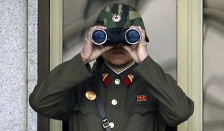 A North Korean soldier looks at the southern side through a pair of binoculars at the border village of Panmunjom, which has separated the two Koreas since the Korean War. (Associated Press)