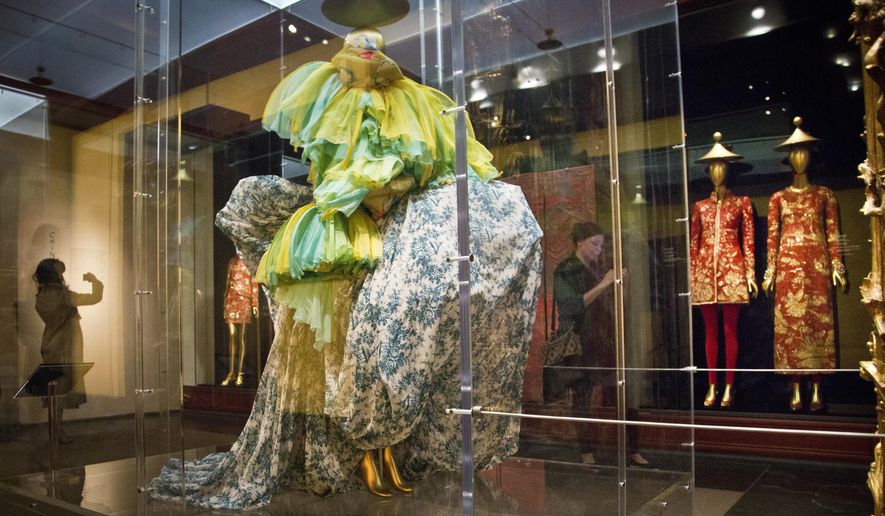 A 2003 haute couture ensemble from designer John Galliano, left, shares space with a 1996-97 Karl Lagerfeld designed dress and evening gown pair, right, on display during the press preview for the Metropolitan Museum's Costume Institute exhibition "China: Through the Looking Glass," Monday, May 4, 2015, in New York. (AP Photo/Bebeto Matthews)