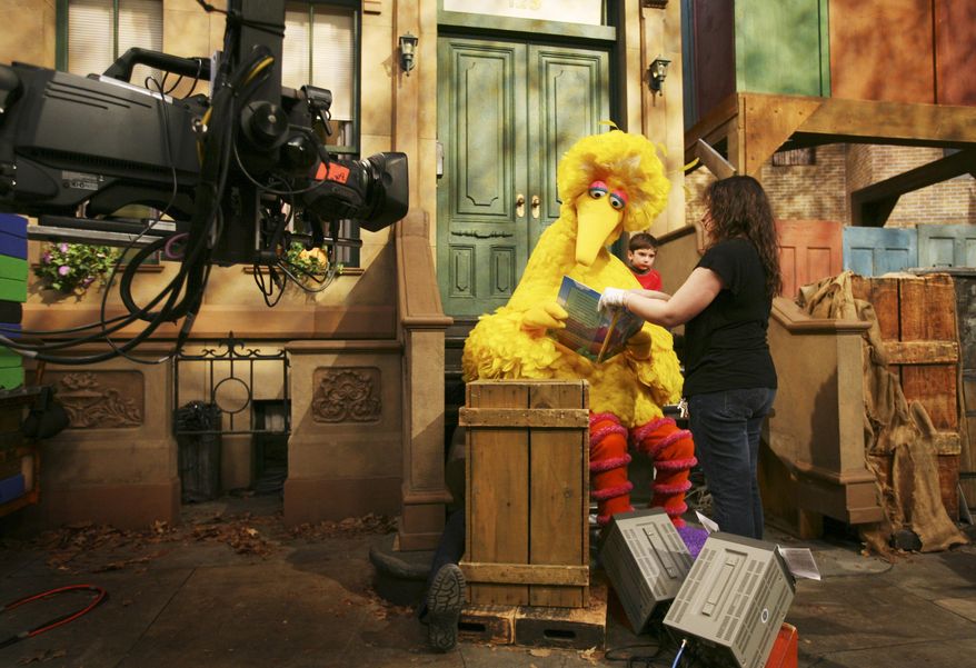 FILE - In this April 10, 2008 file photo, Michelle Hickey, a Muppet wrangler adjusts a book for Big Bird, voiced by Carroll Spinney, so he can read to Connor Scott during a taping of Sesame Street in New York. Spinney drops his fine-feathered obscurity (and emerges from his garbage-can fortress as Oscar the Grouch) for an enchanting film portrait, "I Am Big Bird: The Caroll Spinney Story," which celebrates the "Sesame Street" puppet master who, at age 81, continues to breathe life into a pair of the world's best-loved personalities. (AP Photo/Mark Lennihan, File)
