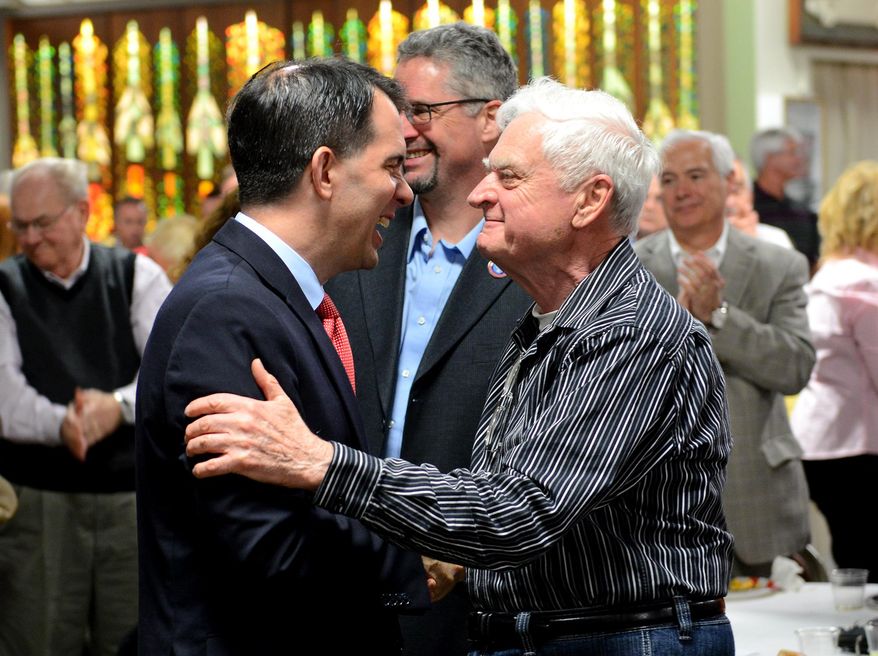 Wisconsin Governor Scott Walker laughs Monday, May 4, 2015, as he shakes hands with an audience member who was at the R.E. Olds Transportation Museum in Lansing to hear him speak during a lunch hosted by the Ingham County Republican Party. Walker, a likely candidate for the Republican nomination for president, spoke on the economy, international relations and more. (Dave Wasinger/Lansing State Journal via AP) MANDATORY CREDIT NO SALES