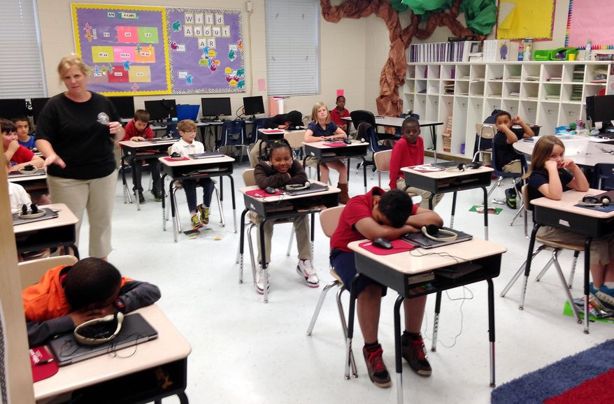 In this April 14, 2015 photograph, third grade students in Stephanie Slayter’s class at Cherokee Elementary School in Pascagoula, Miss., wait for teachers to pick up computers after completing a computerized 50-question multiple choice third-grade reading test. Across Mississippi, 38,000 third graders, their parents and teachers are waiting to find out whether they’ll be moving on to fourth grade. (AP Photo/Jeff Amy)