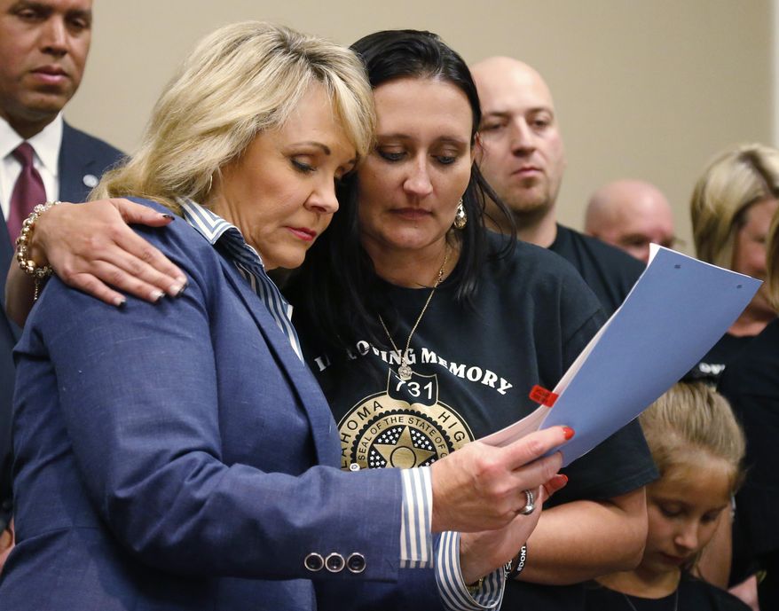 Oklahoma Gov. Mary Fallin, left, and Brandi Dees, right, the widow of Oklahoma State Highway Trooper Nicholas Dees, embrace as they look over a bill banning texting and driving which Fallin signed into law in Oklahoma City, Tuesday, May 5, 2015. Trooper Nicholas Dees was killed and Trooper Keith Burch was injured when they were struck by a vehicle on Interstate 40 in January 2015, whose driver was allegedly updating a social media page at the time. (AP Photo/Sue Ogrocki)