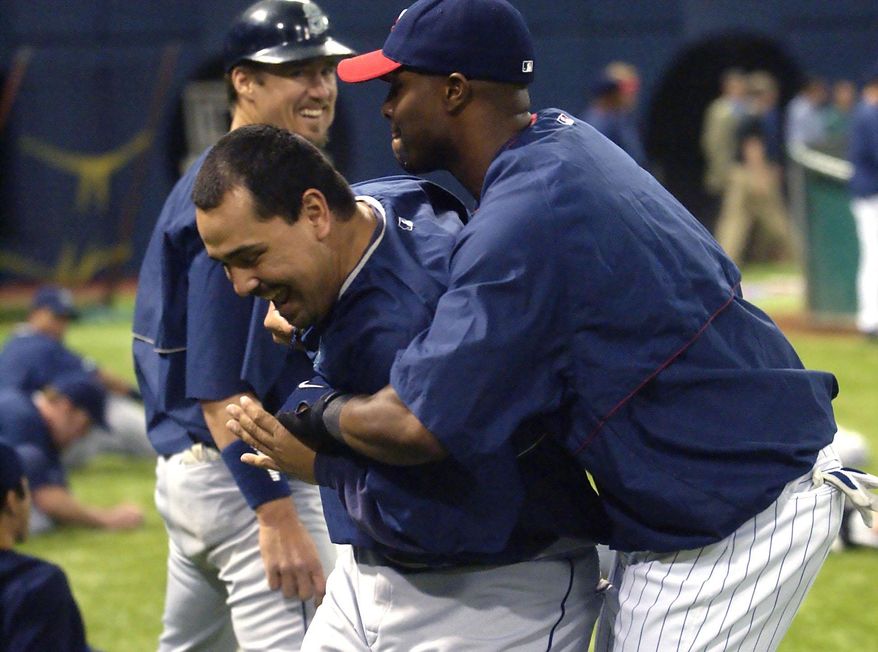 FILE - In this May 11, 2004, file photo, Minnesota Twins' Torii Hunter, right, tackles former teammate, Seattle Mariners closer Eddie Guardado, center, as Mariners catcher Pat Borders, rear, watches prior to the Twins game against the Mariners in Minneapolis. Guardado fondly recalled the scrappy, spunky 2002 Twins that reached the American League Championship Series after the franchise was considered for elimination the preceding winter. Torii Hunter, who returned to the Twins this season after a seven-year absence, was on that team, too. Hiring Guardado as the bullpen coach and signing Hunter to play right field was designed, in part, for the sake of camaraderie and personality on a squad that averaged 96 losses the past four seasons. (AP Photo/Ann Heisenfelt, File)