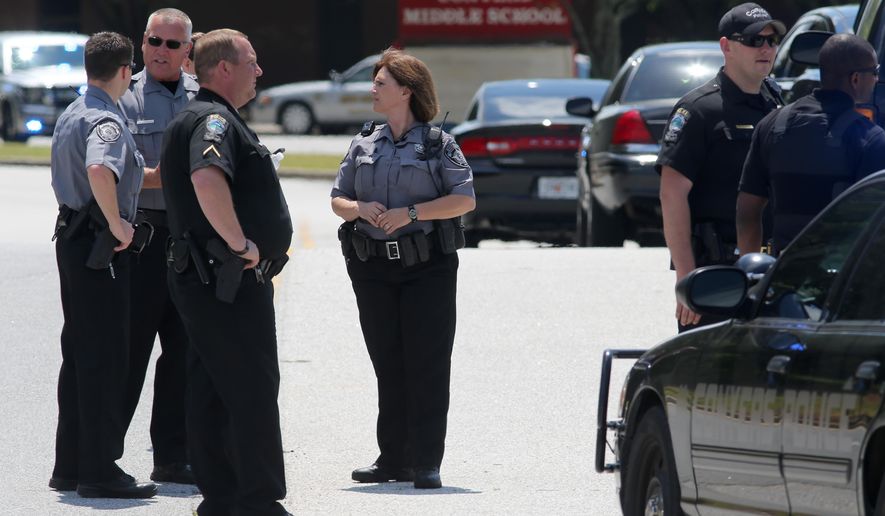 Conyers Police and Rockdale County Sheriff's deputies block the exit from Conyers Middle School on Tuesday, May 5, 2015 after a shot was fired inside the school in Conyers, Ga. Cpl. Michael Camp with the Rockdale County Sheriff's office says a single shot was fired inside a boys' restroom at the school. Camp says a student has been taken into custody, and no injuries have been reported. (Ben Gray/Atlanta Journal-Constitution via AP) MARIETTA DAILY OUT; GWINNETT DAILY POST OUT; LOCAL TELEVISION OUT; WXIA-TV OUT; WGCL-TV OUT