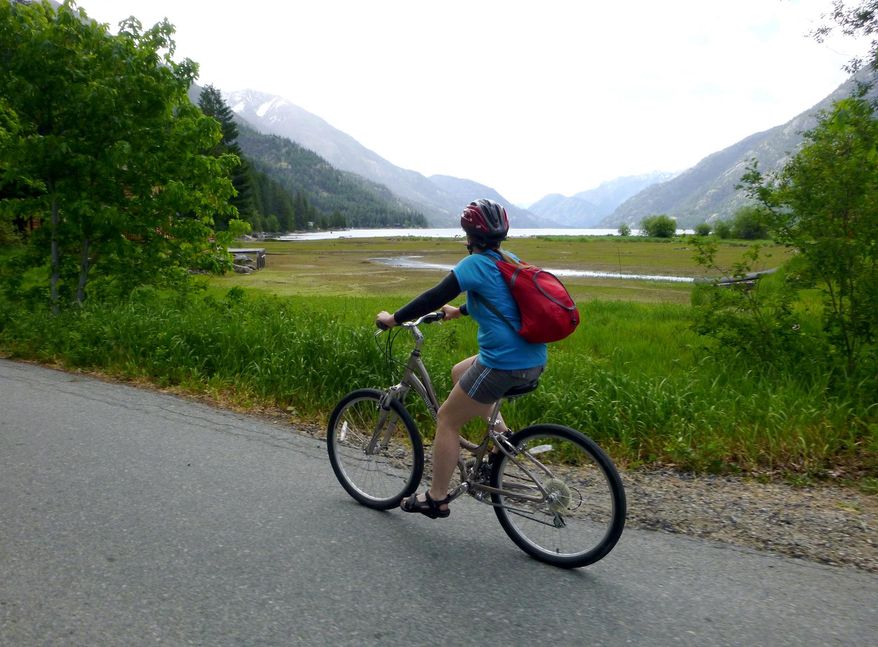 ADVANCE FOR WEEKEND EDITIONS, MAY 9-10 - In this photo taken May 26, 2014, Deb Hansen pedals a rental bike along the road out of Stehekin, Wash., after backpacking the Lake Chelan Lakeshore Trail. Stehekin is a Northwest classic backcountry destination at the end of Lake Chelan, accessible by boat and floatplane and, most deliciously, by foot. (Rich Landers/The Spokesman Review via AP)