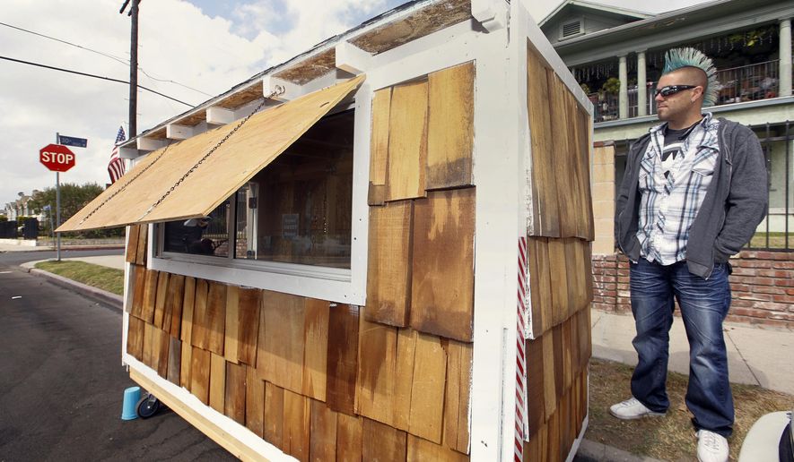 Los Angeles resident Elvis Summers poses with his tiny house on wheels he built for a woman who had been sleeping on the streets in his South Los Angeles neighborhood on Thursday, May 7, 2015. Summers never thought more than 5.6 million people would watch a YouTube video of him constructing the 8-foot-long house for Irene &quot;Smokie&quot; McGhee, 60, a grandmother who’s been homeless for more than a decade. He estimates he spent less than $500 on plywood, shingles, a window and a door. (AP Photo/Damian Dovarganes)