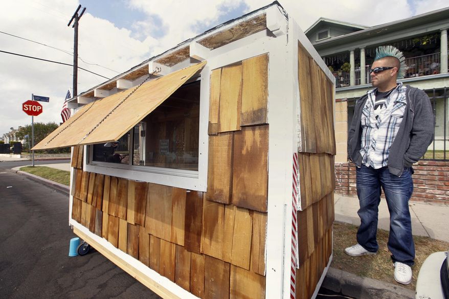 Los Angeles resident Elvis Summers poses with his tiny house on wheels he built for a woman who had been sleeping on the streets in his South Los Angeles neighborhood on Thursday, May 7, 2015. Summers never thought more than 5.6 million people would watch a YouTube video of him constructing the 8-foot-long house for Irene "Smokie" McGhee, 60, a grandmother who’s been homeless for more than a decade. He estimates he spent less than $500 on plywood, shingles, a window and a door. (AP Photo/Damian Dovarganes)