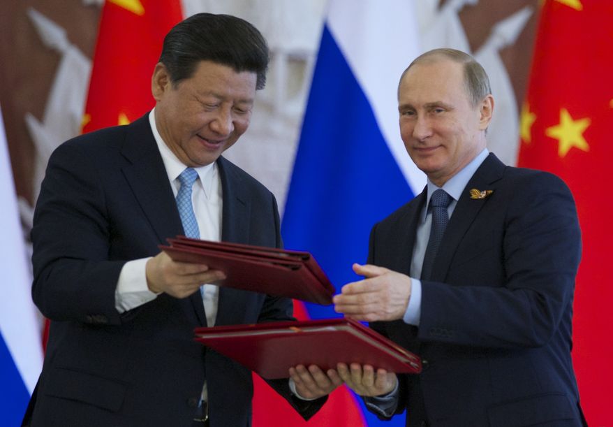 Russian President Vladimir Putin, right, and Chinese President Xi Jinping exchange documents at the signing ceremony in the Kremlin in Moscow, Friday, May 8, 2015. Russian and Chinese leaders have signed a plethora of deals in Moscow, giving Russia billions in infrastructure loans. (Associated Press) ** FILE **