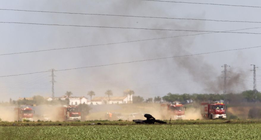 Emergency services personnel work in the area after a plane crash near Seville airport, in Spain, Saturday, May 9, 2015. A military transport plane crashed near southwestern Seville airport Saturday, killing its crew, Spain's prime minister said. It is unclear if any others were injured. Mariano Rajoy said up to 10 crew members were aboard the brand new Airbus A400M aircraft that was undergoing flight trials at the airport. (AP Photo/Miguel Angel Morenatti)