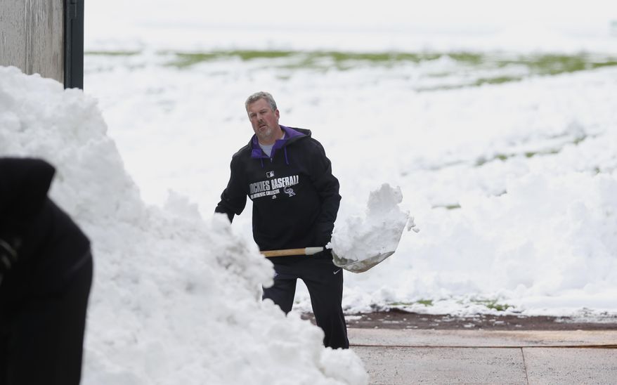Alan Bossart, visiting clubhouse manager for the Colorado Rockies, shovels snow off the outfield in Coors Field after a wet, heavy snow Sunday, May 10, 2015, in Denver. Groundskeepers are hurrying to prepare the field for the baseball game scheduled for Sunday between the Los Angeles Dodgers and the Rockies. The spring storm that left the snow in Denver has wreaked havoc across the state, triggering flood warnings in northeast counties while dropping up to 18 inches of snow in the southern parts of the Centennial State. (AP Photo/David Zalubowski)