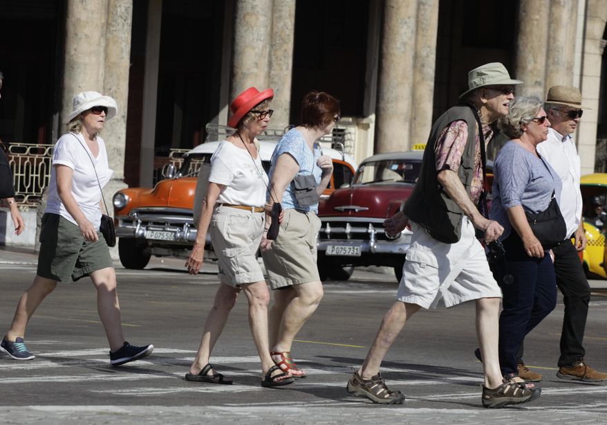FILE - In this March 13, 2015 file photo, tourists cross traffic lights in Havana, Cuba. Tourists in shorts and sandals aren't the only foreigners flooding Havana these days. Top diplomats from Japan, the European Union, Italy, the Netherlands and Russia have visited the island in recent months in a bid to stake out or maintain ties with an island that suddenly looks like a brighter economic prospect amid warming U.S.-Cuba relations. (AP Photo/Desmond Boylan, File)