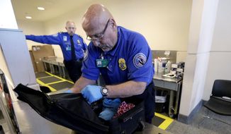 A TSA agent checks a bag at a security checkpoint area at Midway International Airport in Chicago. Two TSA managers say they were punished after exposing major security problems at the Minneapolis-St. Paul International Airport. (Associated Press)