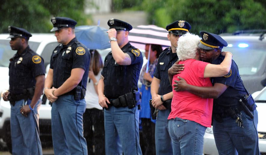 A woman hugs an officer during the procession for the body of Hattiesburg Police Officer Benjamin Deen, Monday, May 11, 2015, in Hattiesburg, Miss. Marvin Banks faces two counts of capital murder in the Saturday shootings of Officers Deen and Liquori Tate following a traffic stop. (Eli Baylis/The Hattiesburg American via AP) NO SALES